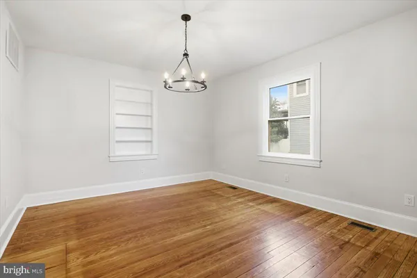 a view of empty room with wooden floor and window