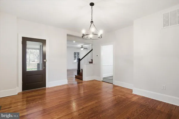 a view of a room with wooden floor staircase and a chandelier