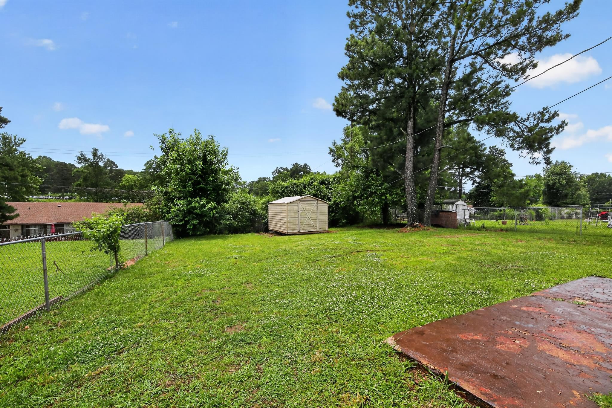 645 Parkrose Road Memphis, TN 38109 - Photo 6 of 32 Expansive backyard featuring a manicured lawn, established trees, and a utility shed