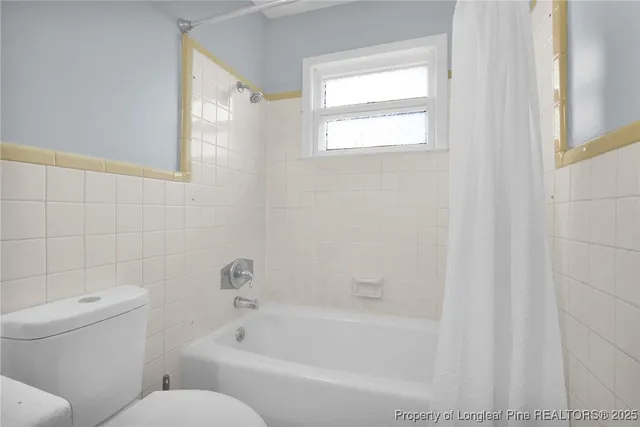 a white bath tub sitting next to a white toilet and a shower