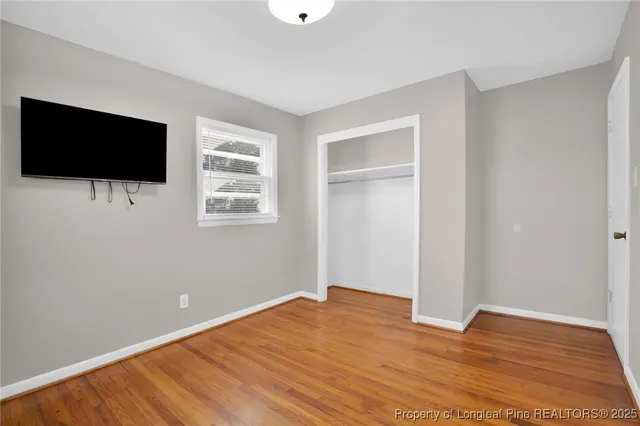 a view of empty room with wooden floor and flat screen tv