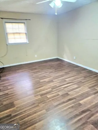 an empty room with wooden floor chandelier fan and windows