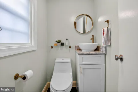 a bathroom with a toilet sink vanity and mirror