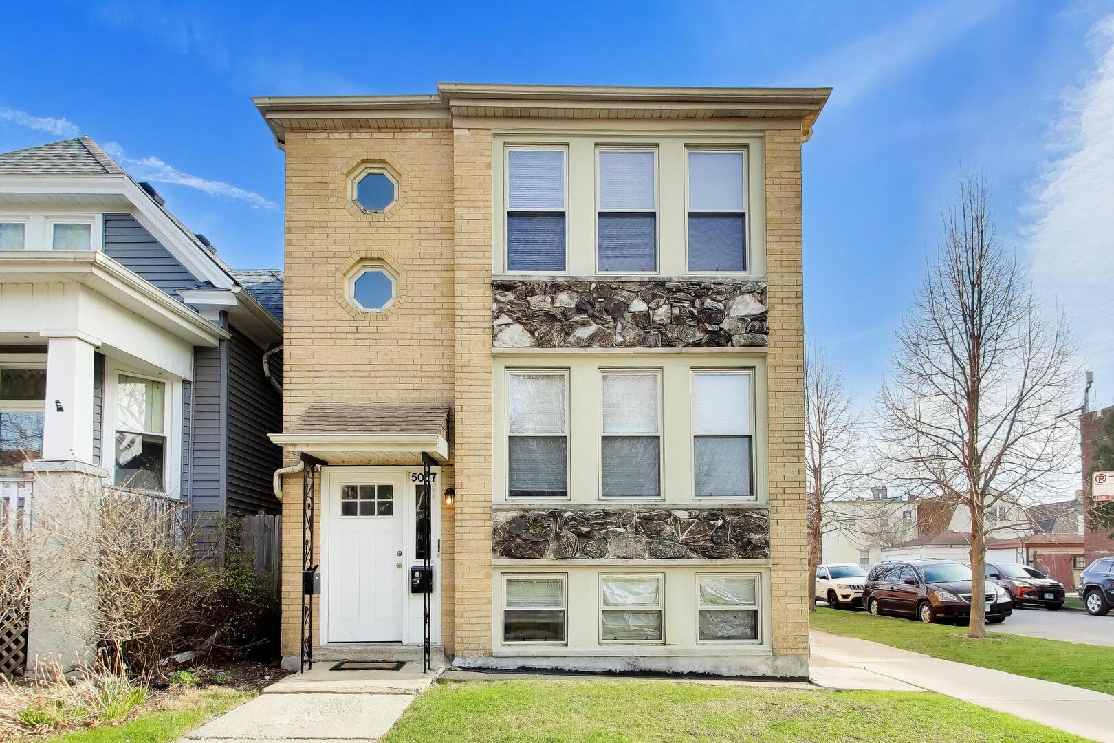 5057 West Dakin Street, Unit G Chicago, IL 60641 - Photo 1 of 19 a front view of a house with a yard