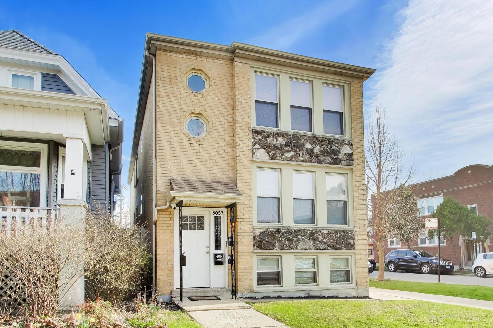 5057 West Dakin Street, Unit G Chicago, IL 60641 - Photo 2 of 19 a front view of a building with a yard