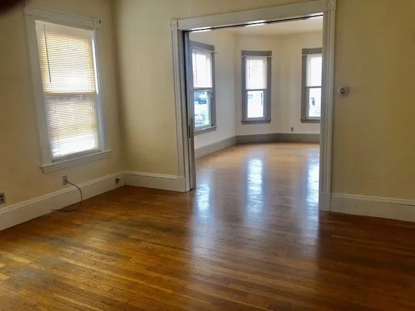an empty room with wooden floor and windows