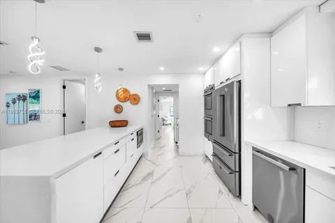 a kitchen with stainless steel appliances kitchen island granite countertop a refrigerator and a sink