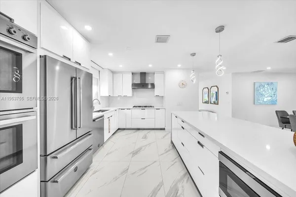a large white kitchen with stainless steel appliances