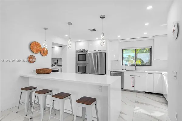 a kitchen with stainless steel appliances kitchen island granite countertop a sink and a refrigerator