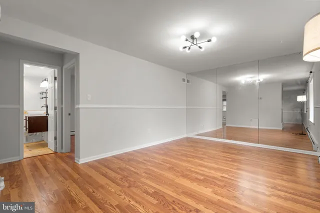 a view of an empty room with wooden floor and a kitchen