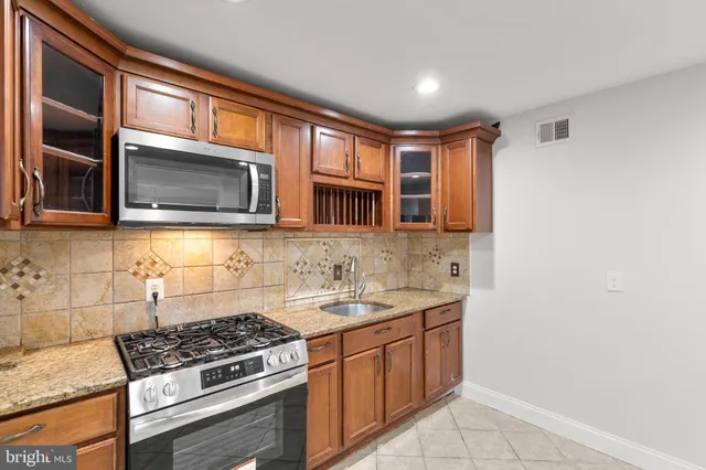 a kitchen with stainless steel appliances granite countertop a stove microwave and sink