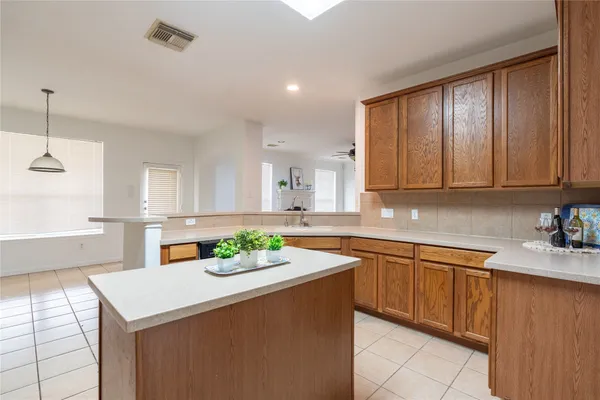 a kitchen with stainless steel appliances granite countertop wooden cabinets a sink a stove a dining table and chairs