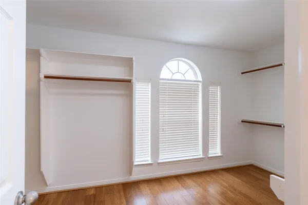 an empty room with wooden floor chandelier and windows