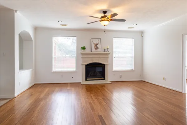 an empty room with windows fireplace and wooden floor