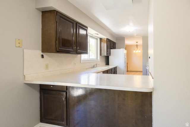 634 South 2100th Street West Vernal, UT 84078 - Photo 16 of 71 Kitchen featuring dark wood cabinetry, light-toned countertops, and a white sink with a window above