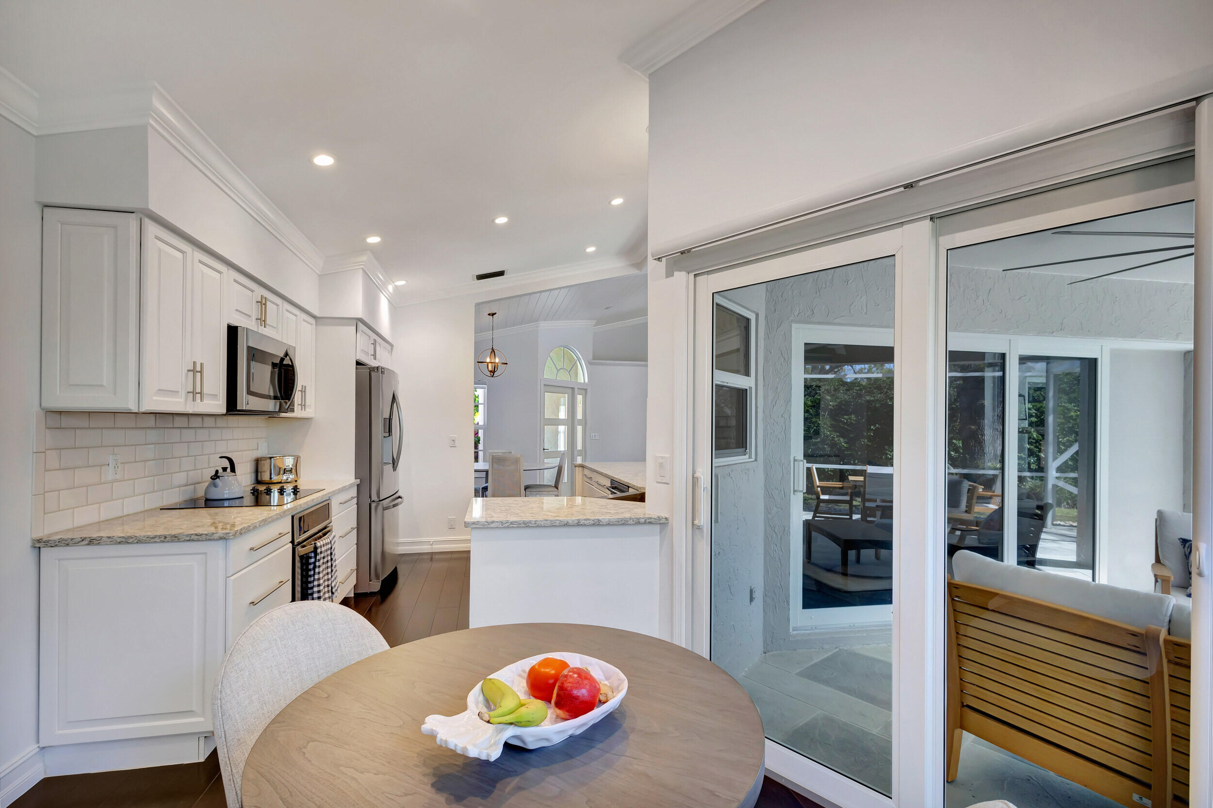 16501 Riverwind Drive Jupiter, FL 33477 - Photo 21 of 50 a kitchen with stainless steel appliances granite countertop a sink a stove a refrigerator cabinets and living room view