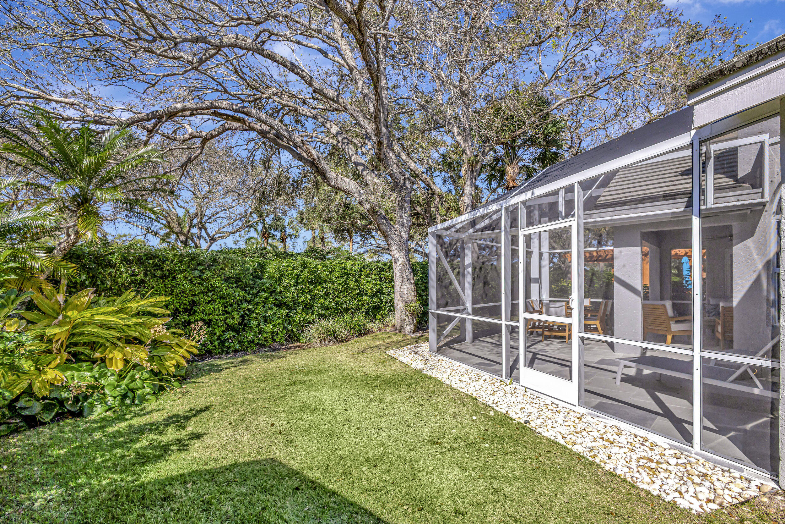 16501 Riverwind Drive Jupiter, FL 33477 - Photo 41 of 50 a backyard of a house with plants and large trees