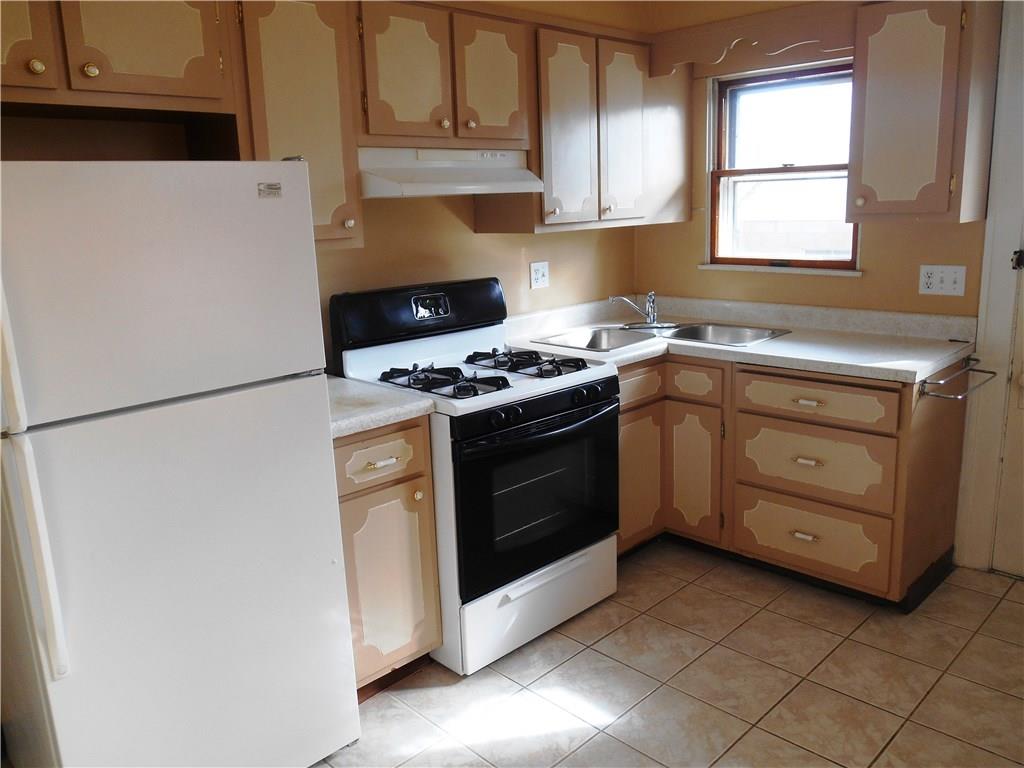 1165 Race Street McKees Rocks, PA 15136 - Photo 9 of 25 The kitchen comes with the gas stove and refrigerator. Tile floor and door to the back yard and garage.