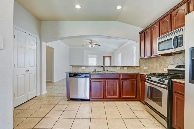 a kitchen with stainless steel appliances granite countertop a stove top oven a sink and dishwasher