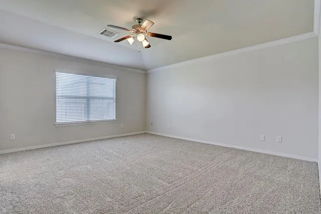 an empty room with a chandelier fan and windows