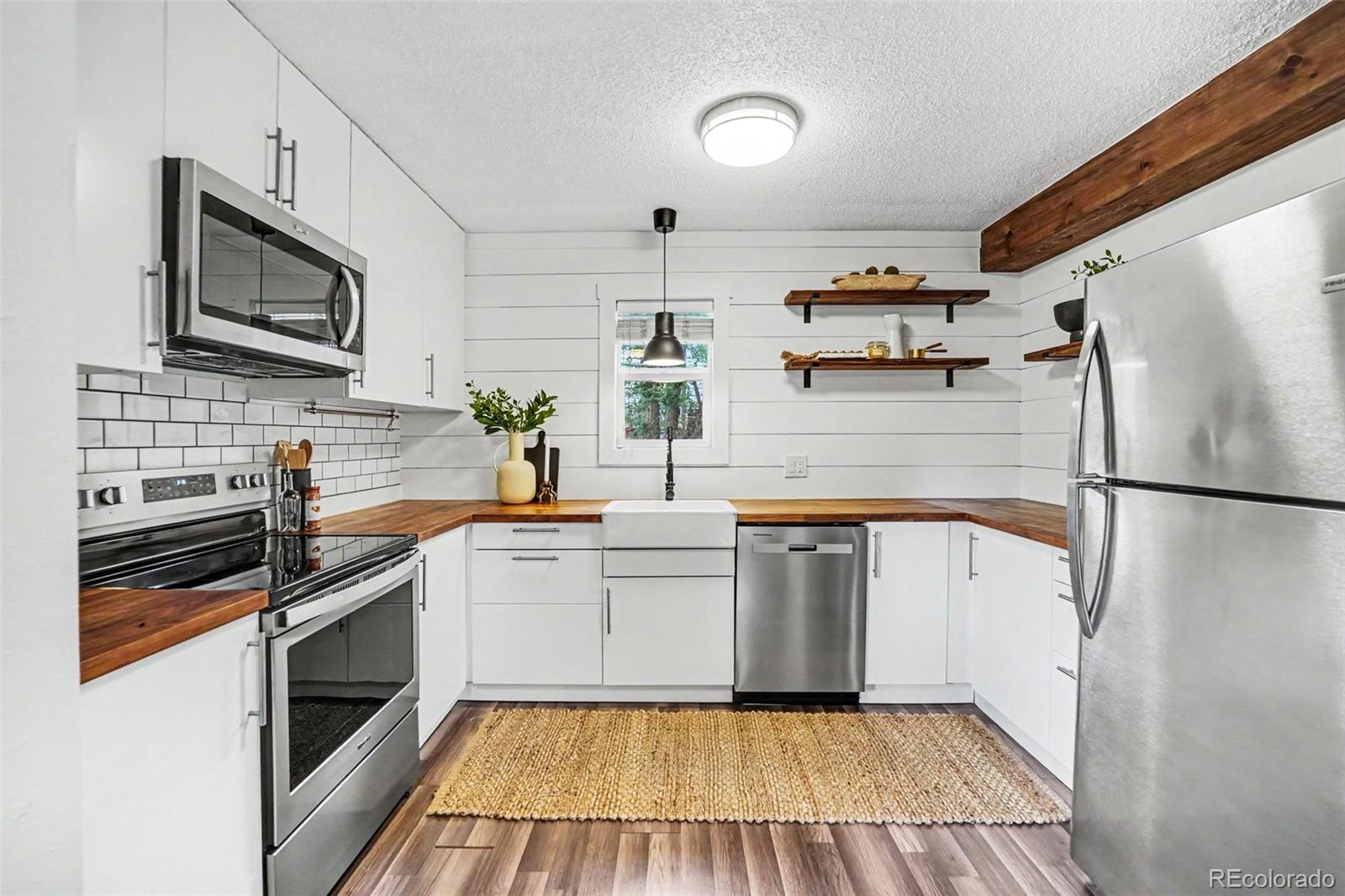5700 West 28th Avenue, Unit 1 Wheat Ridge, CO 80214 - Photo 14 of 25 a kitchen with white cabinets and stainless steel appliances
