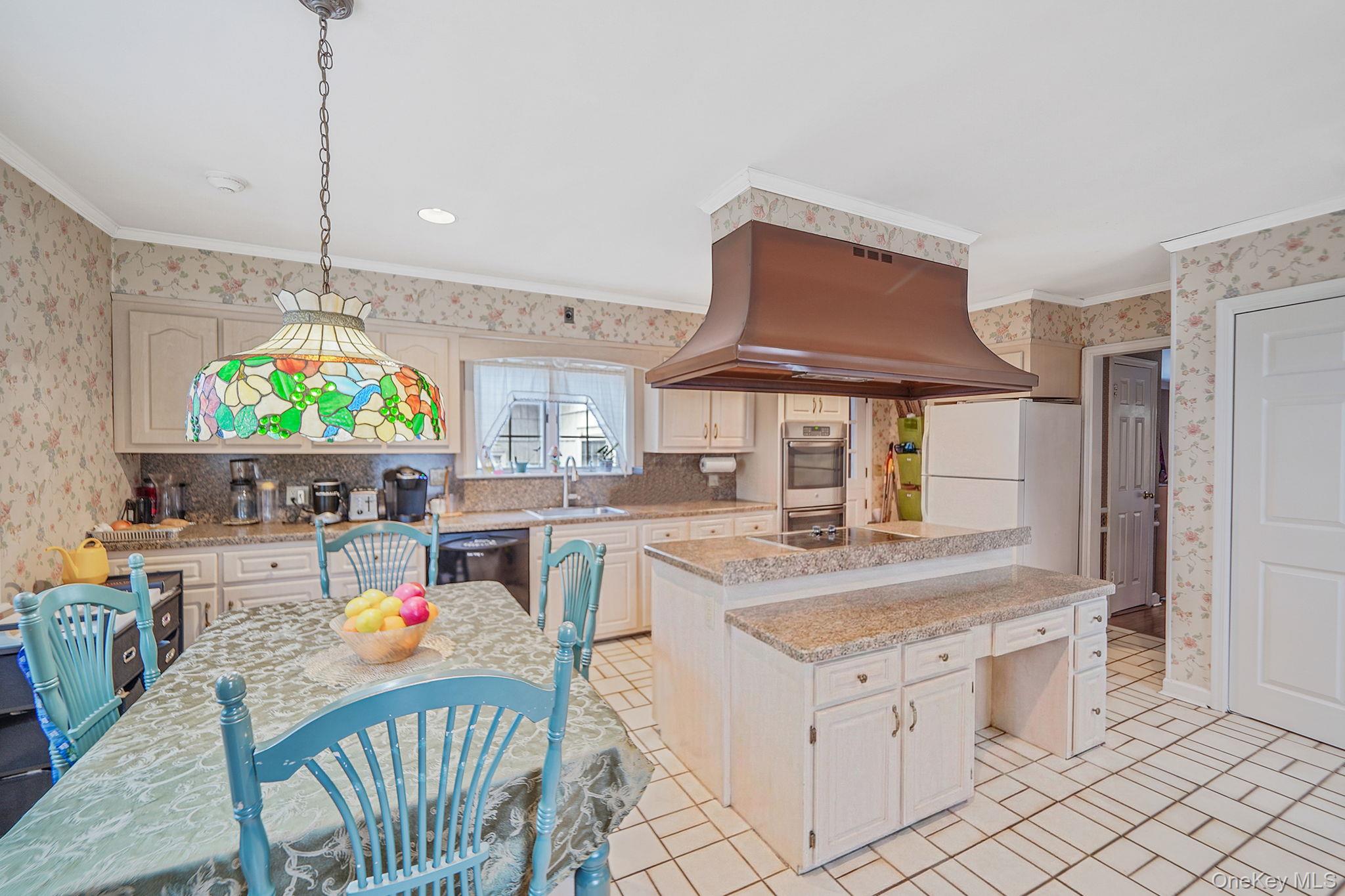 7 Rugby Road Westbury, NY 11590 - Photo 12 of 46 Kitchen with wallpapered walls, freestanding refrigerator, a kitchen island, island range hood, and pendant lighting