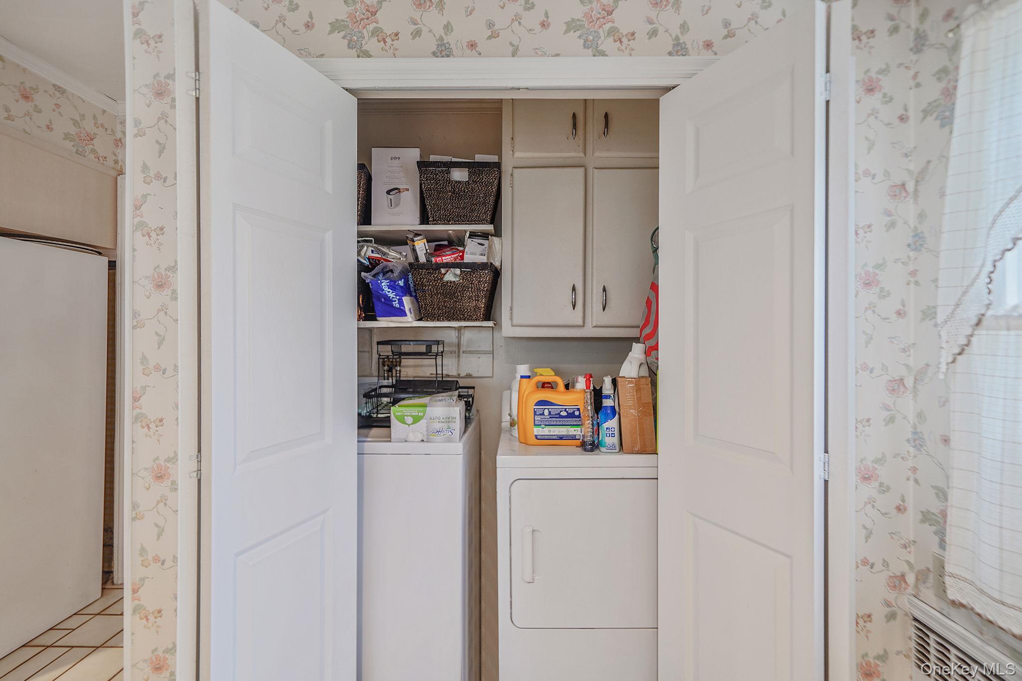 7 Rugby Road Westbury, NY 11590 - Photo 13 of 46 Laundry area with wallpapered walls, cabinet space, light tile patterned flooring, and washer and dryer