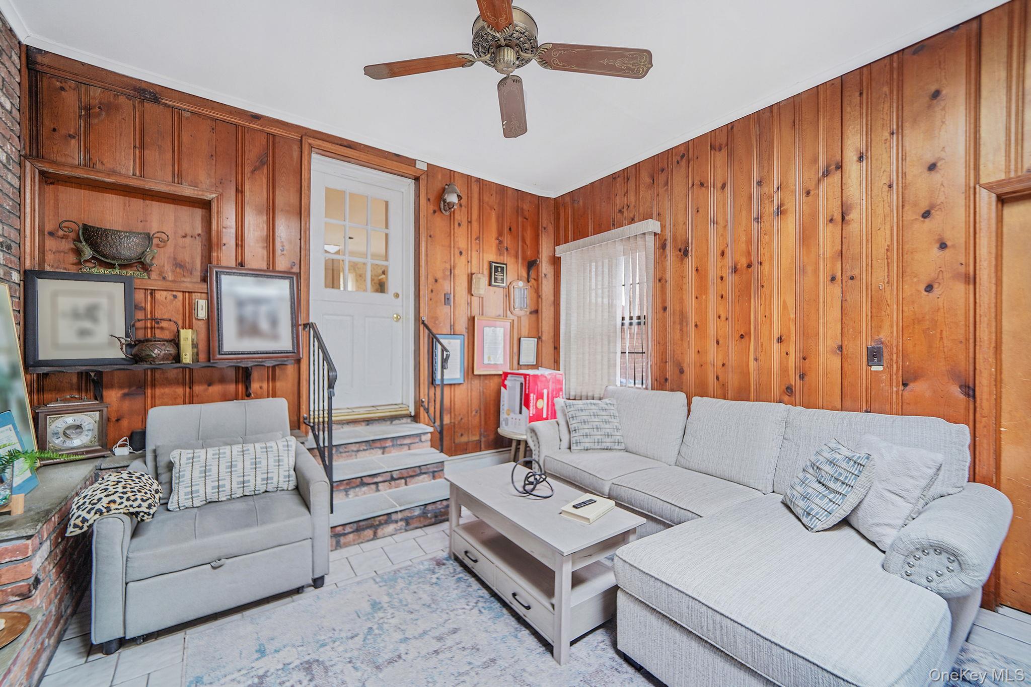 7 Rugby Road Westbury, NY 11590 - Photo 14 of 46 Living room featuring wooden walls, stairway, and ceiling fan