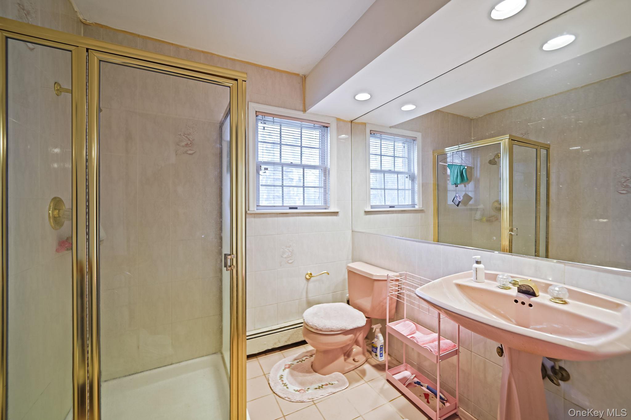 7 Rugby Road Westbury, NY 11590 - Photo 18 of 46 Full bath featuring tile walls, light tile patterned floors, baseboard heating, a stall shower, and recessed lighting