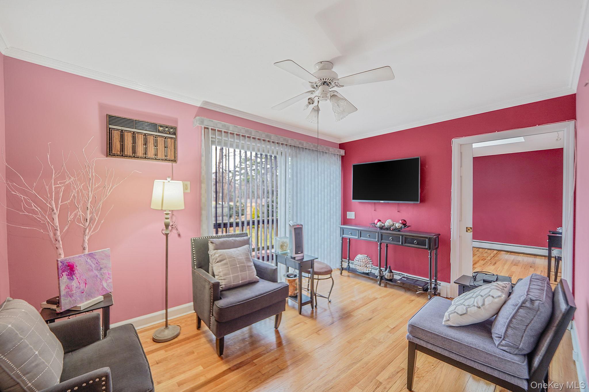 7 Rugby Road Westbury, NY 11590 - Photo 20 of 46 Living area featuring ornamental molding, wood finished floors, ceiling fan, and a baseboard heating unit