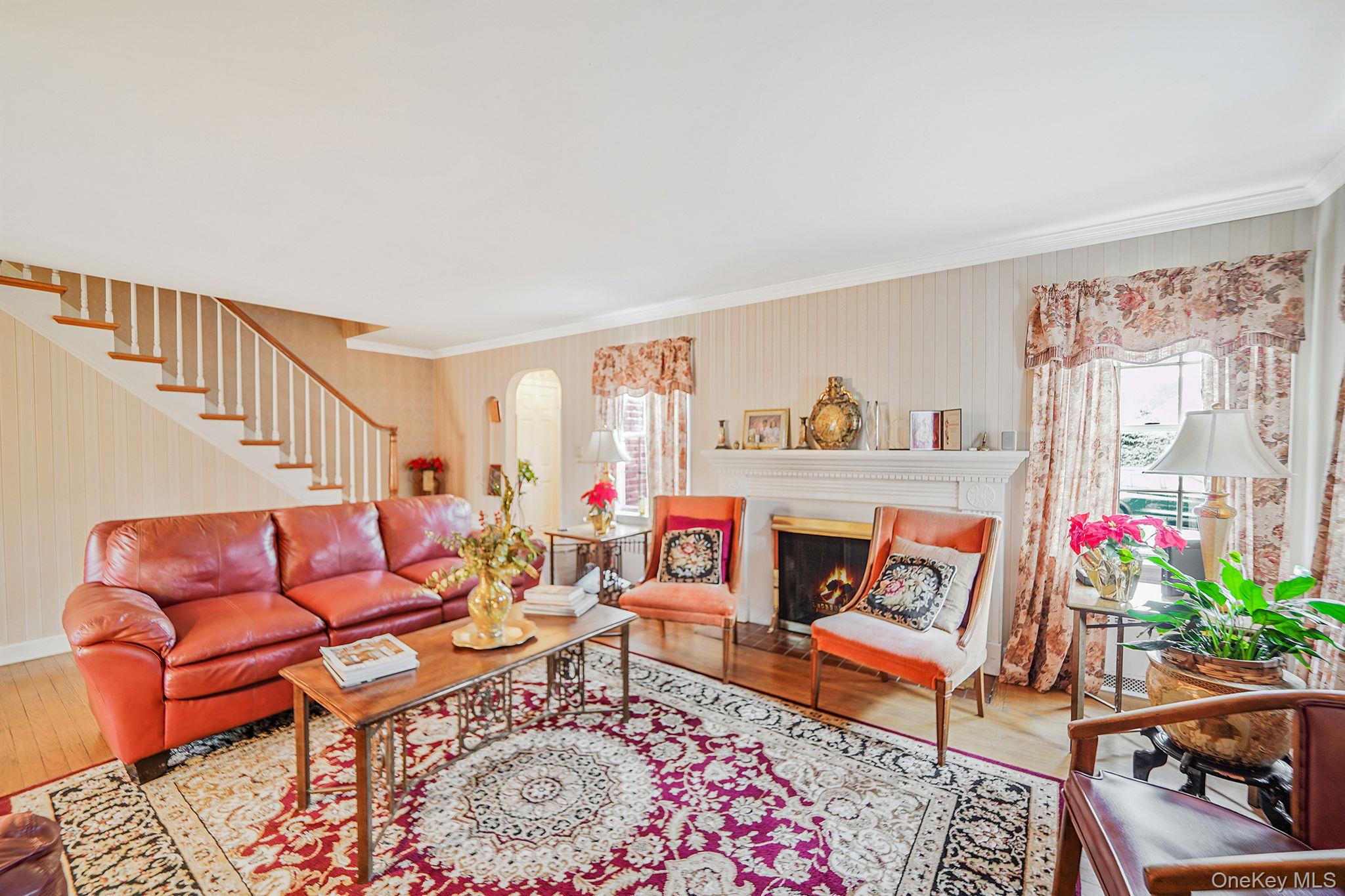 7 Rugby Road Westbury, NY 11590 - Photo 2 of 46 Living room with a warm lit fireplace, stairs, ornamental molding, and hardwood / wood-style floors