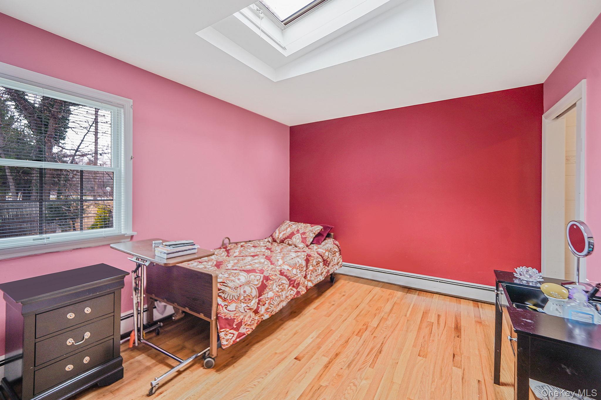 7 Rugby Road Westbury, NY 11590 - Photo 22 of 46 Bedroom featuring a skylight, a baseboard radiator, light wood-style floors, and an office area