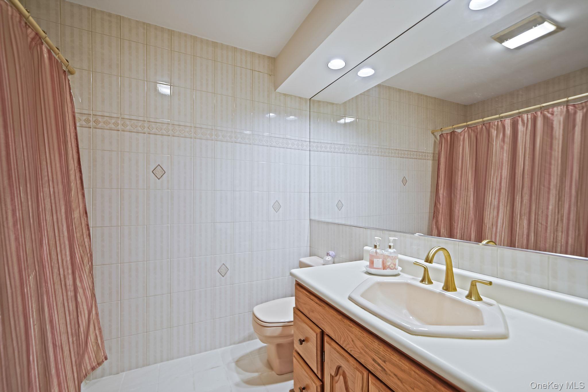 7 Rugby Road Westbury, NY 11590 - Photo 23 of 46 Full bath with vanity, tile walls, curtained shower, recessed lighting, and light tile patterned floors