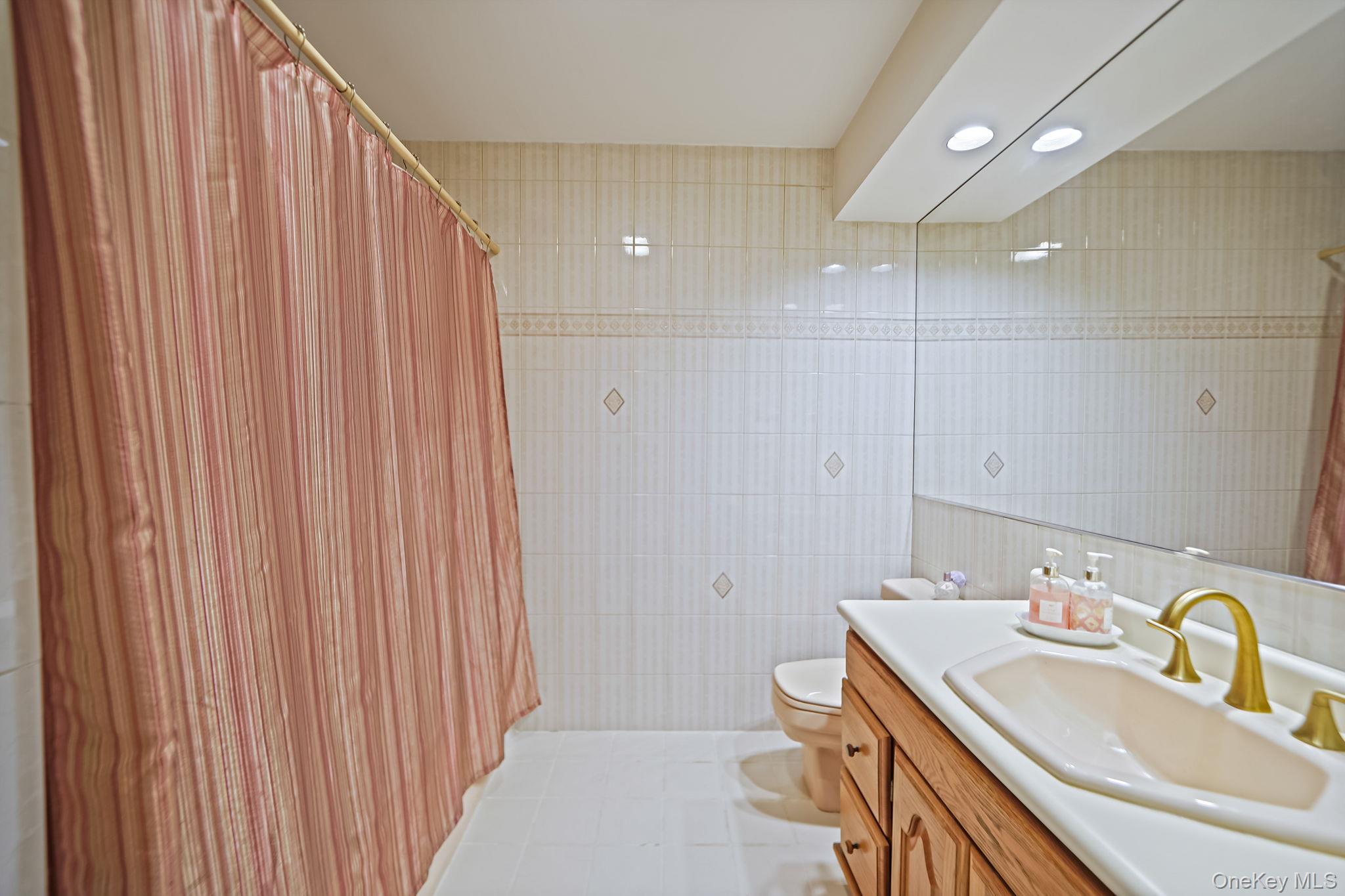7 Rugby Road Westbury, NY 11590 - Photo 24 of 46 Full bathroom with vanity, tile walls, light tile patterned flooring, and recessed lighting