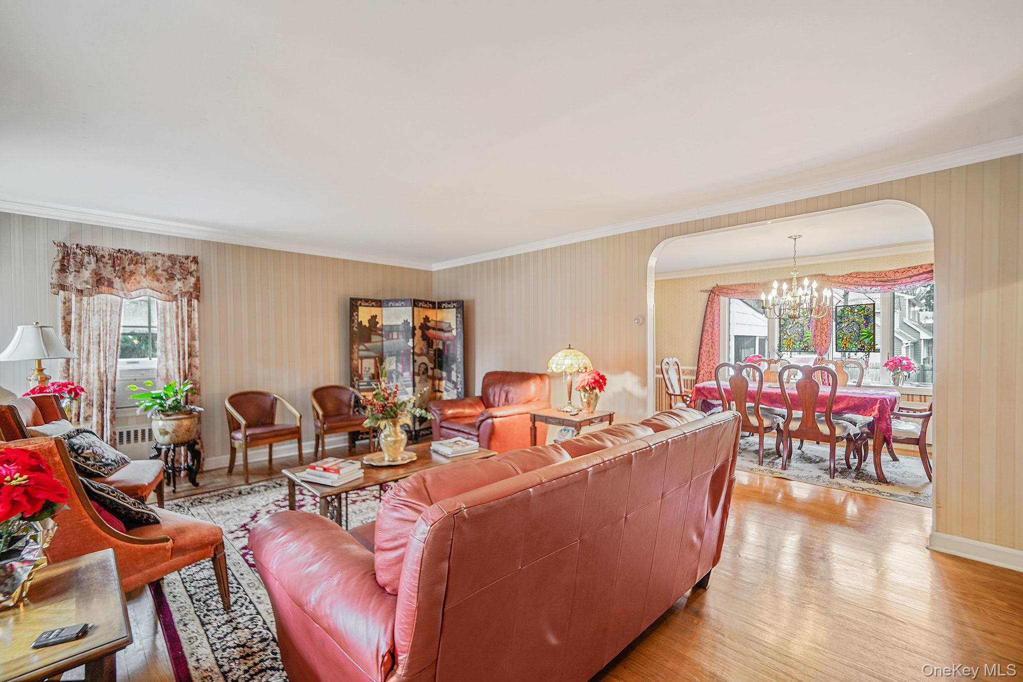 7 Rugby Road Westbury, NY 11590 - Photo 3 of 46 Living room featuring arched walkways, wood finished floors, a chandelier, and crown molding