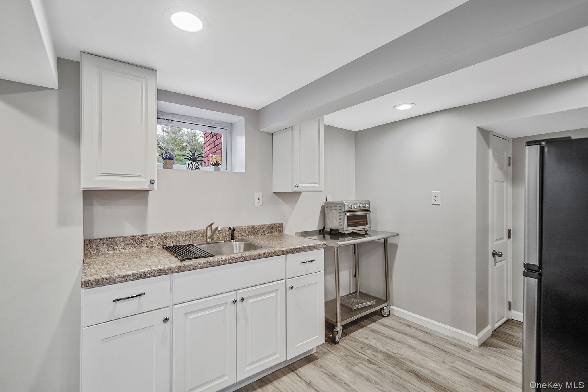7 Rugby Road Westbury, NY 11590 - Photo 35 of 46 Kitchen featuring freestanding refrigerator, white cabinetry, light wood-style flooring, and recessed lighting