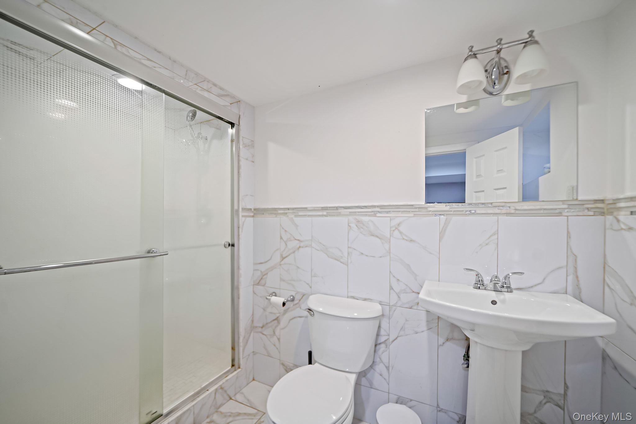 7 Rugby Road Westbury, NY 11590 - Photo 39 of 46 Bathroom featuring tile walls, a stall shower, and a wainscoted wall