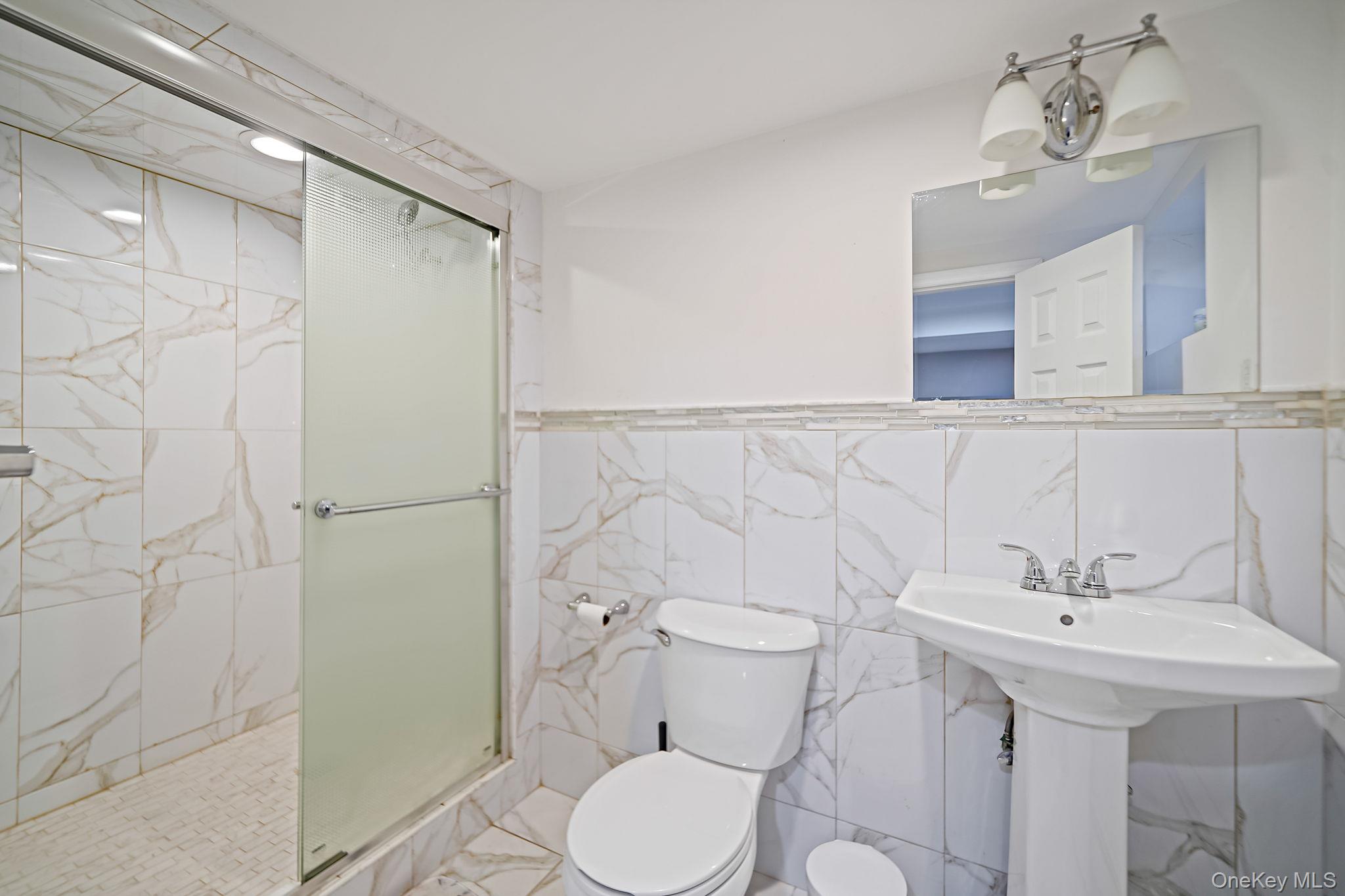 7 Rugby Road Westbury, NY 11590 - Photo 40 of 46 Full bath with tile walls, a marble finish shower, and a wainscoted wall