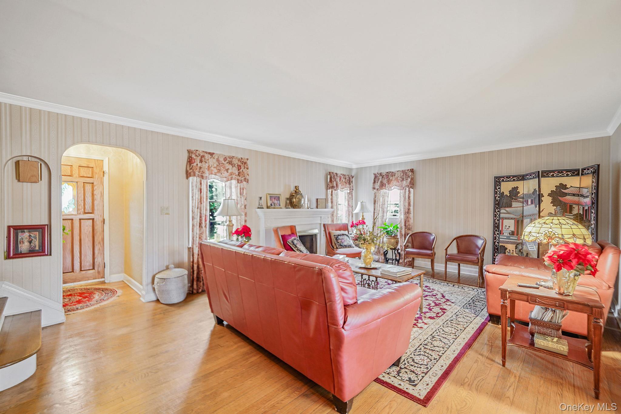 7 Rugby Road Westbury, NY 11590 - Photo 5 of 46 Living room with light wood-type flooring, arched walkways, a fireplace, and ornamental molding