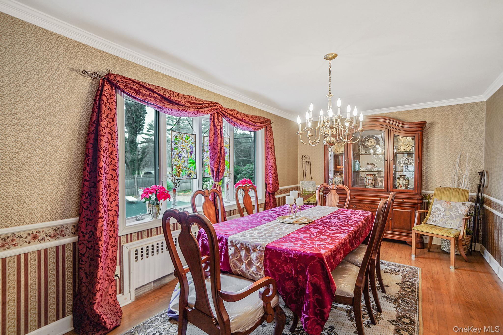 7 Rugby Road Westbury, NY 11590 - Photo 6 of 46 Dining space with wallpapered walls, a chandelier, a wainscoted wall, wood finished floors, and crown molding