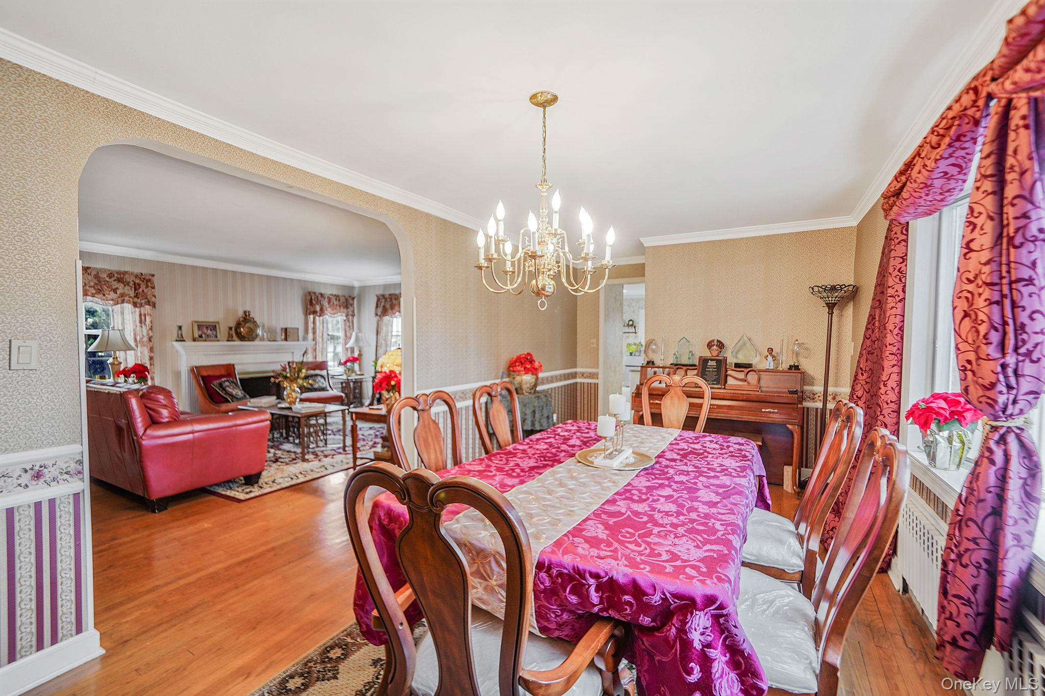 7 Rugby Road Westbury, NY 11590 - Photo 7 of 46 Dining space featuring arched walkways, wallpapered walls, ornamental molding, light wood finished floors, and a chandelier