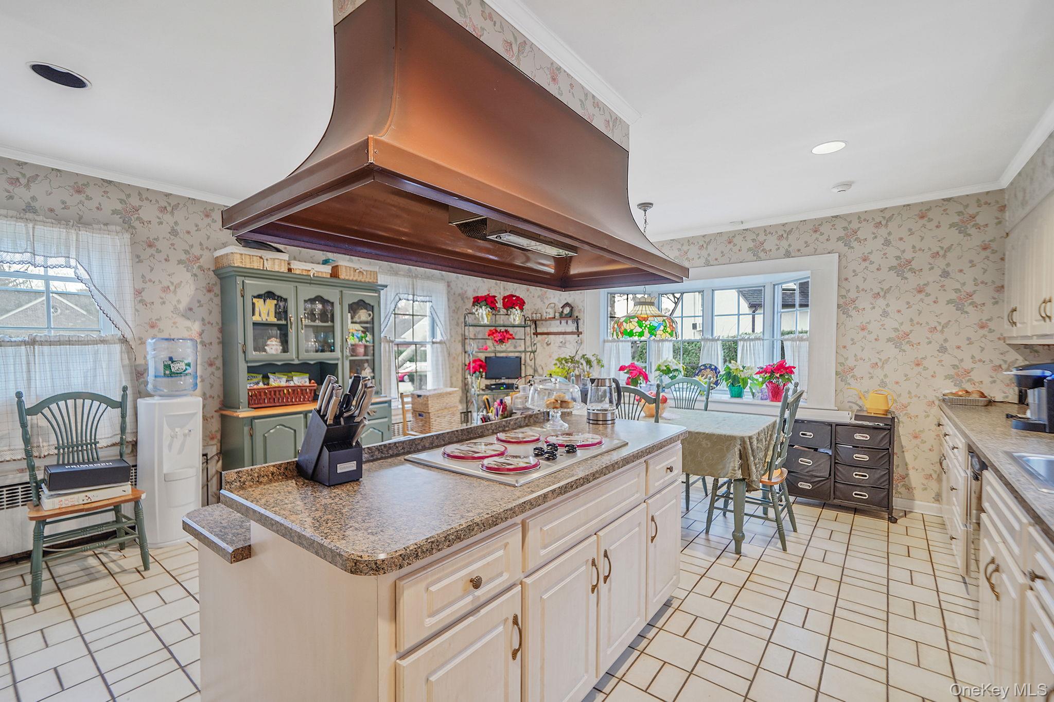 7 Rugby Road Westbury, NY 11590 - Photo 8 of 46 Kitchen with ventilation hood, wallpapered walls, a center island, healthy amount of natural light, and ornamental molding