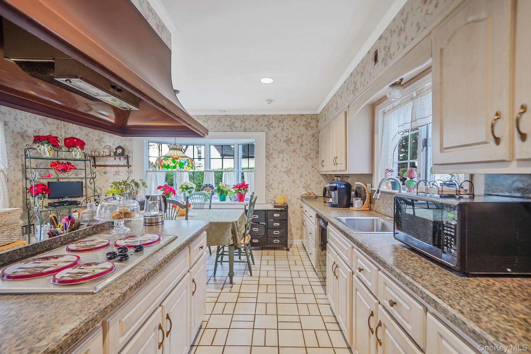7 Rugby Road Westbury, NY 11590 - Photo 10 of 46 Kitchen featuring wallpapered walls, under cabinet range hood, black microwave, stainless steel electric stovetop, and light stone countertops