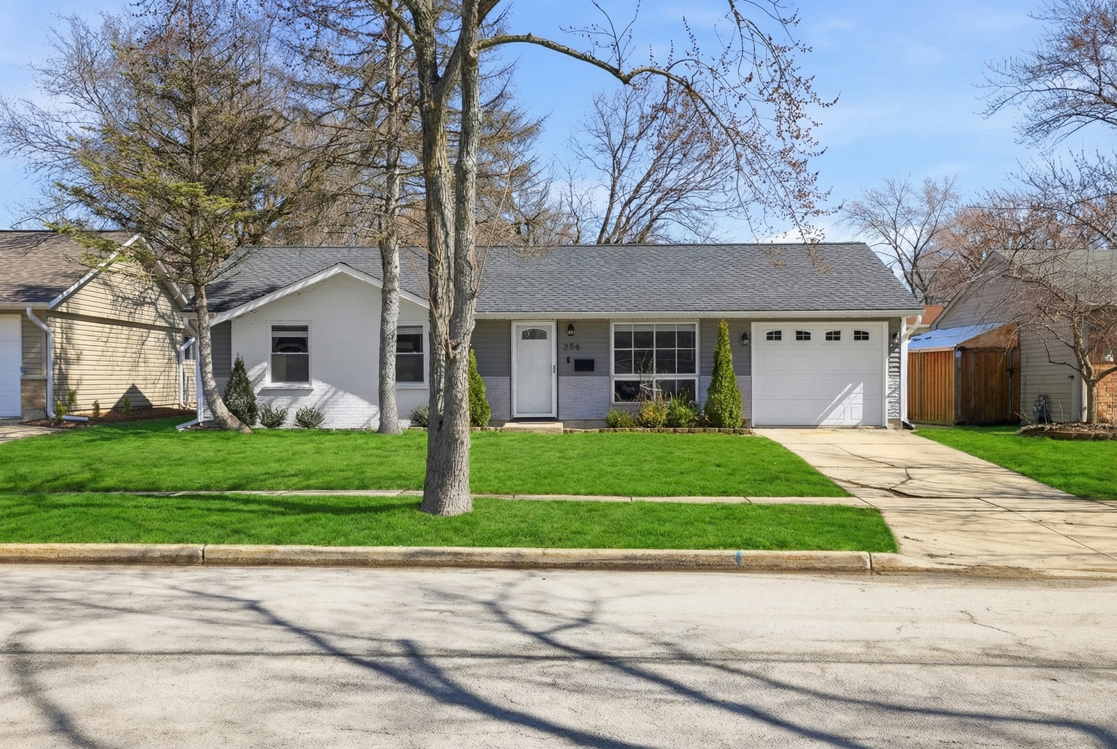 a front view of a house with a garden and trees