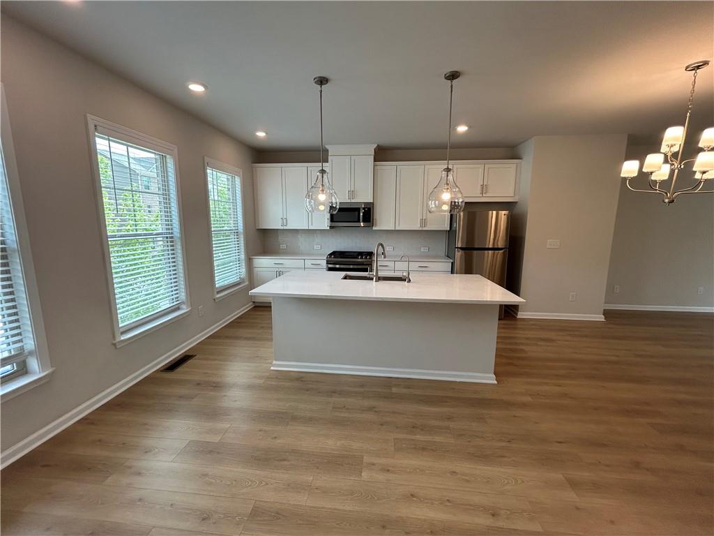 3715 Davis Circle Duluth, GA 30096 - Photo 6 of 20 a large kitchen with stainless steel appliances kitchen island a large counter top a stove a refrigerator white cabinets and wooden floor
