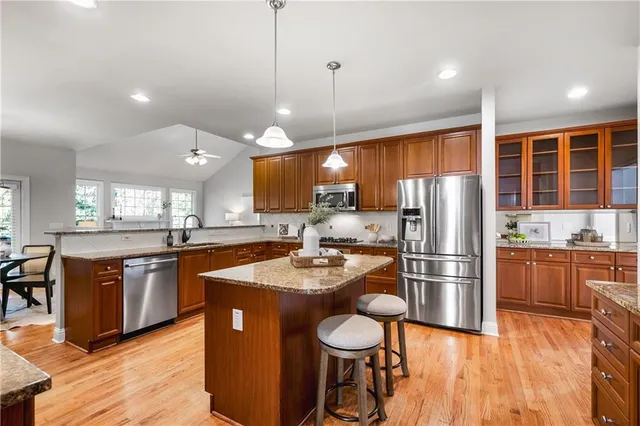 a kitchen with stainless steel appliances granite countertop a refrigerator a sink dishwasher a stove and white countertops with wooden floor