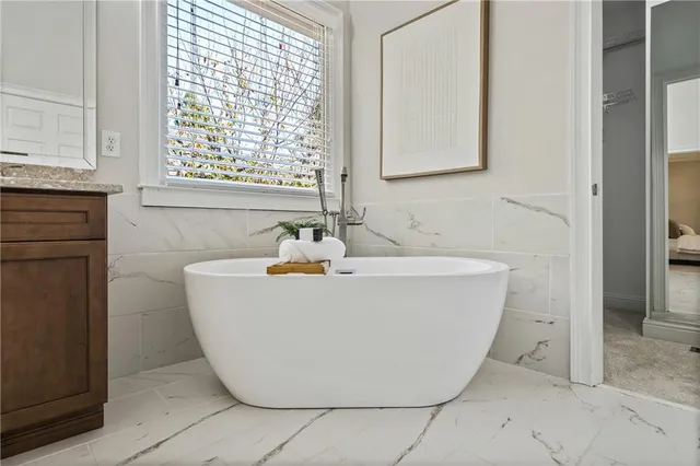 a white bath tub sitting in a bathroom next to a window