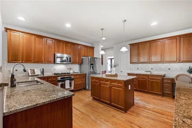 a kitchen with stainless steel appliances granite countertop wooden cabinets a stove a sink and dishwasher