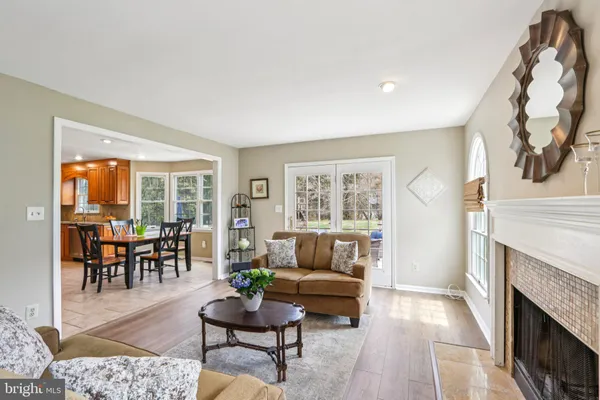 a view of a dining room and livingroom with furniture wooden floor a rug a flat screen tv a rug a fireplace and a chandelier