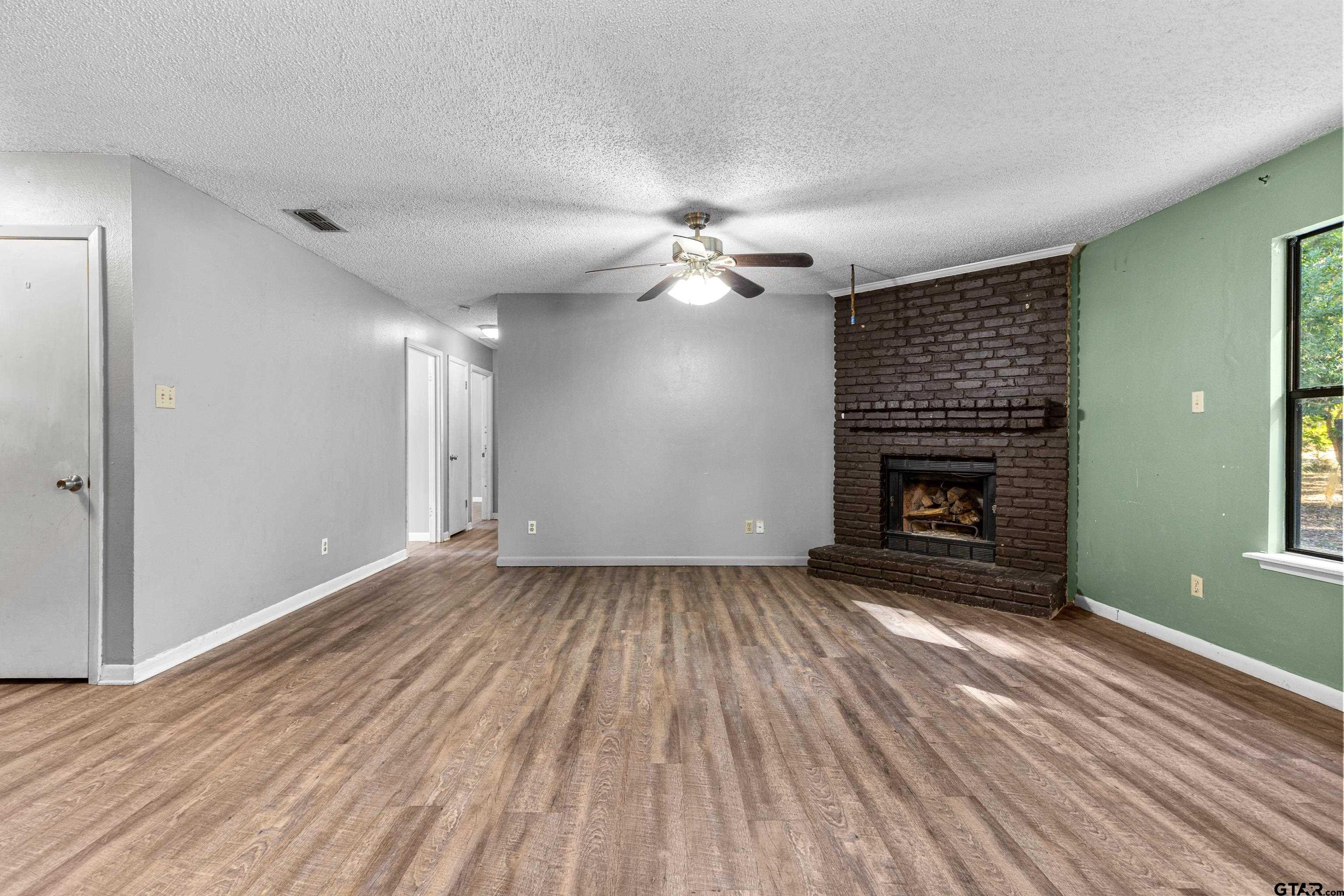 473 Meadow View Path Holly Lake Ranch, TX 75765 - Photo 15 of 37 a view of an empty room with wooden floor fireplace and a window